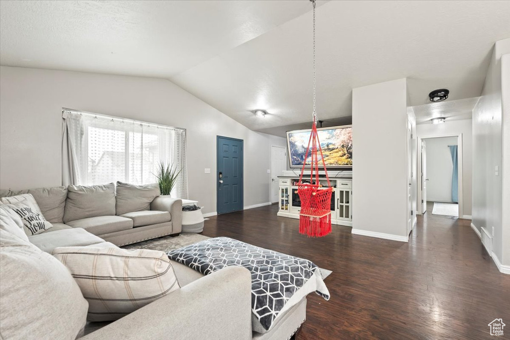 Living area featuring baseboards, vaulted ceiling, and wood finished floors