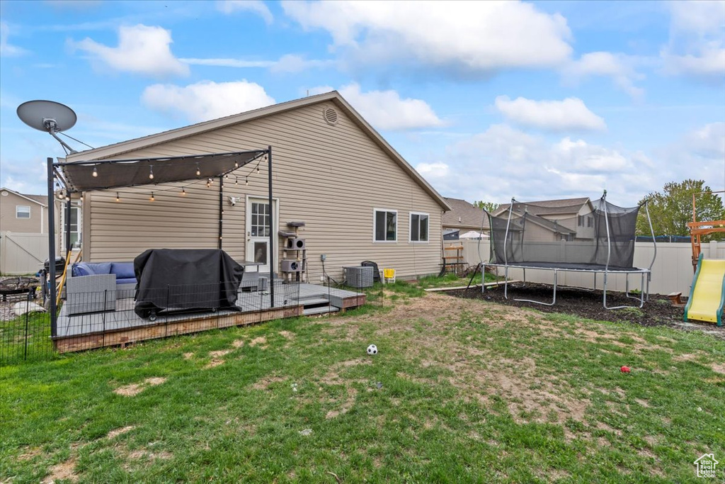 Rear view of property featuring a fenced backyard, a trampoline, and a yard