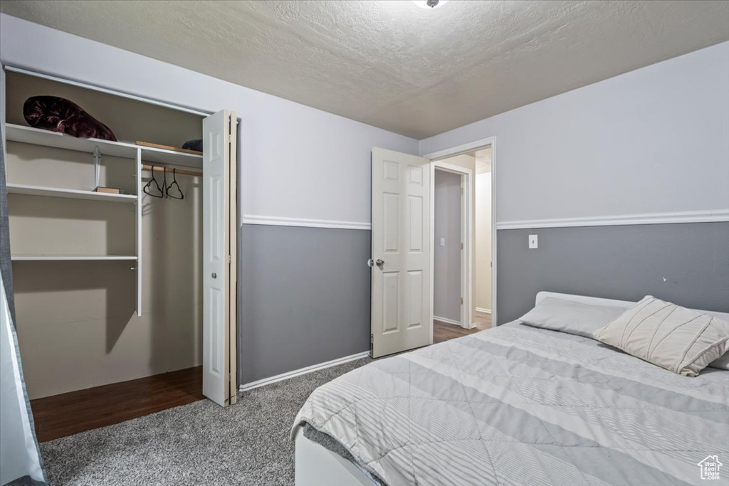 Carpeted bedroom featuring a textured ceiling and a closet