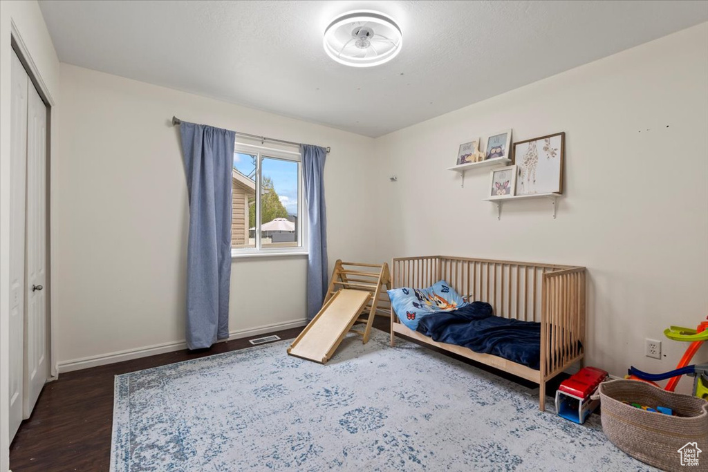 Bedroom featuring visible vents, baseboards, wood finished floors, and a closet