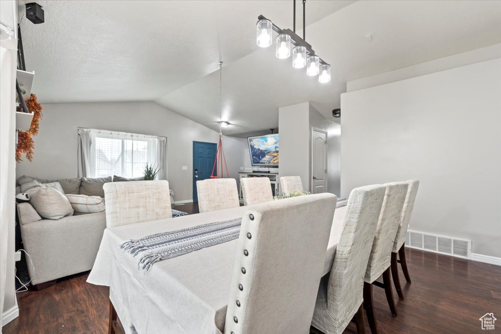 Dining area featuring baseboards, visible vents, dark wood-style floors, and vaulted ceiling