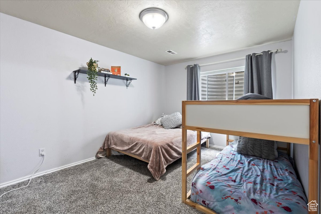 Bedroom featuring visible vents, carpet flooring, baseboards, and a textured ceiling