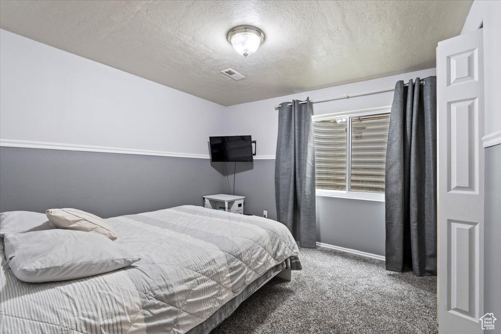 Bedroom featuring baseboards, carpet, a textured ceiling, and visible vents