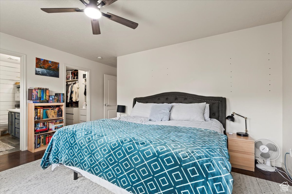 Bedroom featuring a closet, wood finished floors, a walk in closet, connected bathroom, and a ceiling fan