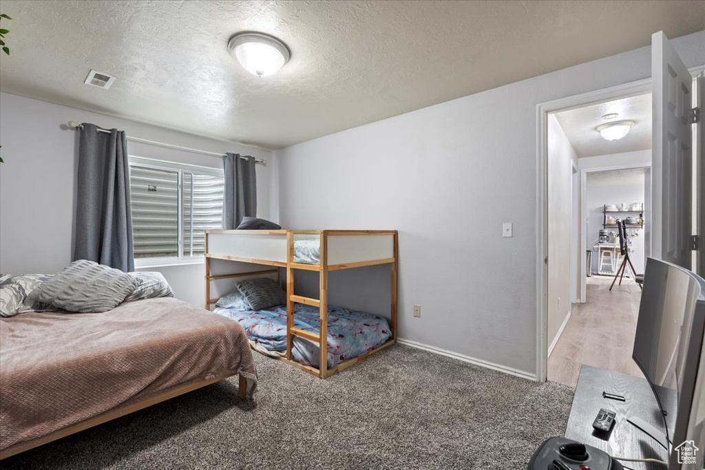 Bedroom featuring baseboards, carpet, a textured ceiling, and visible vents