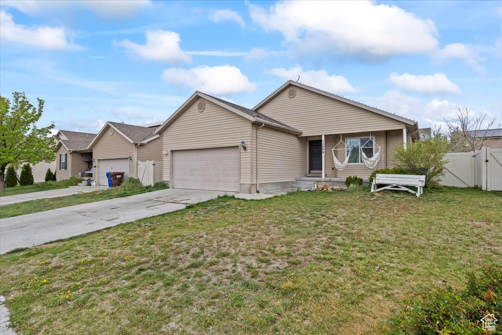View of front of property with fence, a front lawn, a garage, a gate, and driveway