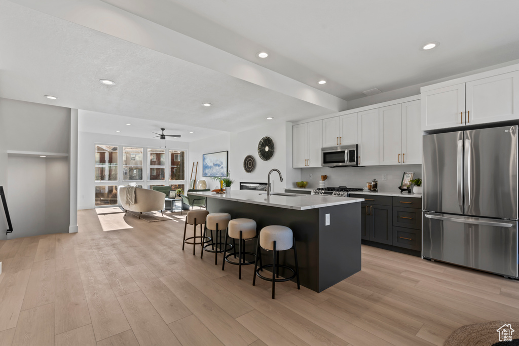 Kitchen featuring a sink, white cabinetry, appliances with stainless steel finishes, and light wood finished floors