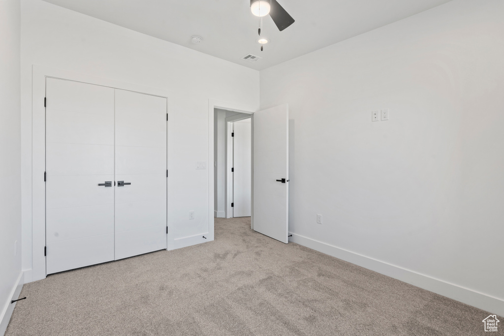 Unfurnished bedroom featuring baseboards, visible vents, a closet, and light colored carpet