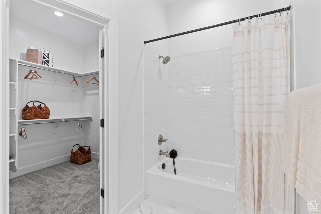Full bath with baseboards, a walk in closet, and shower / bath combo