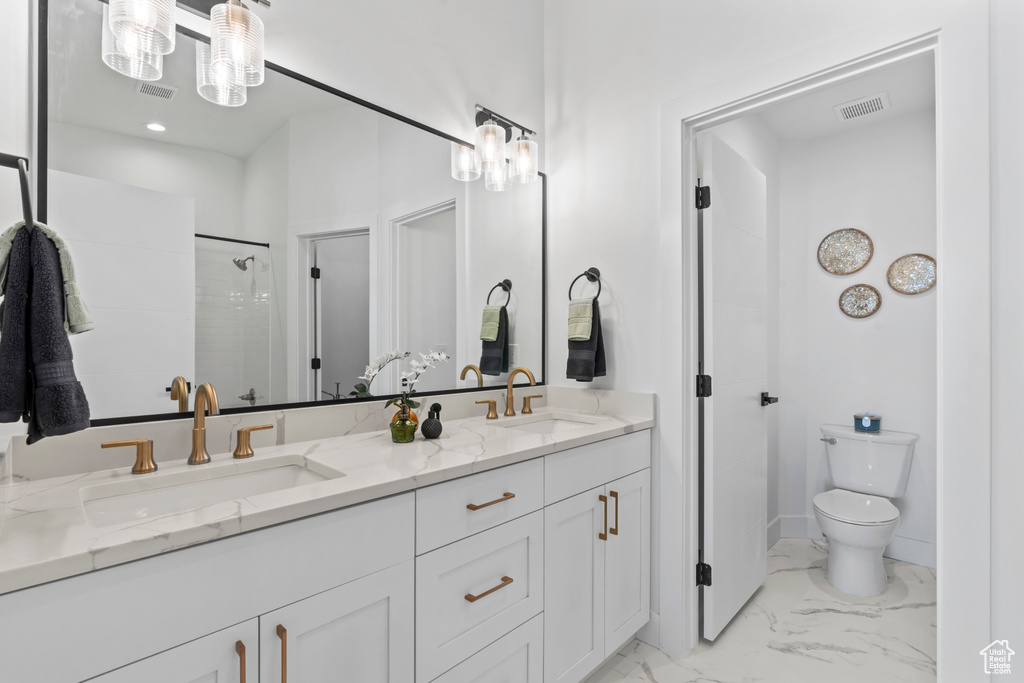 Bathroom featuring a sink, toilet, double vanity, and marble finish floor