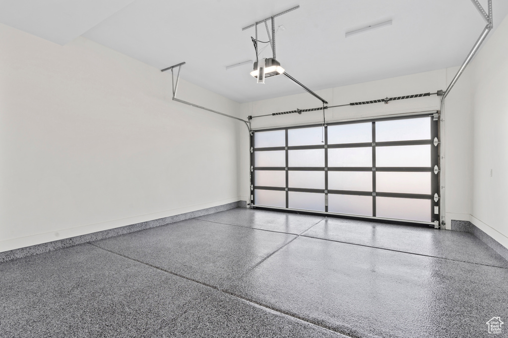 Garage featuring baseboards and a garage door opener