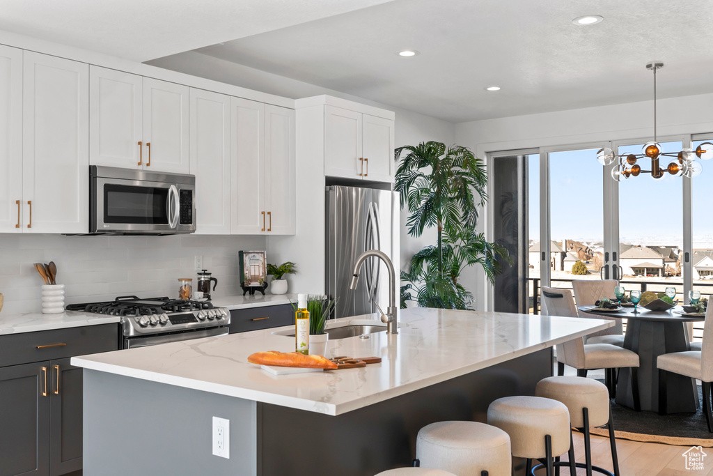 Kitchen featuring decorative backsplash, light stone countertops, a sink, stainless steel appliances, and recessed lighting