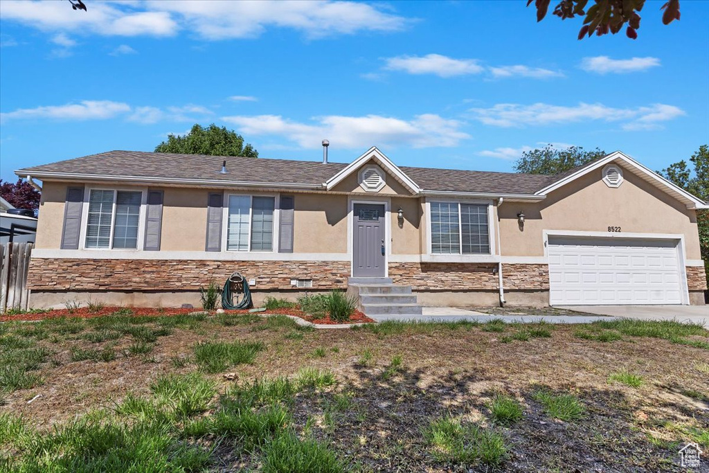 Single story home with stone siding, stucco siding, a garage, and driveway