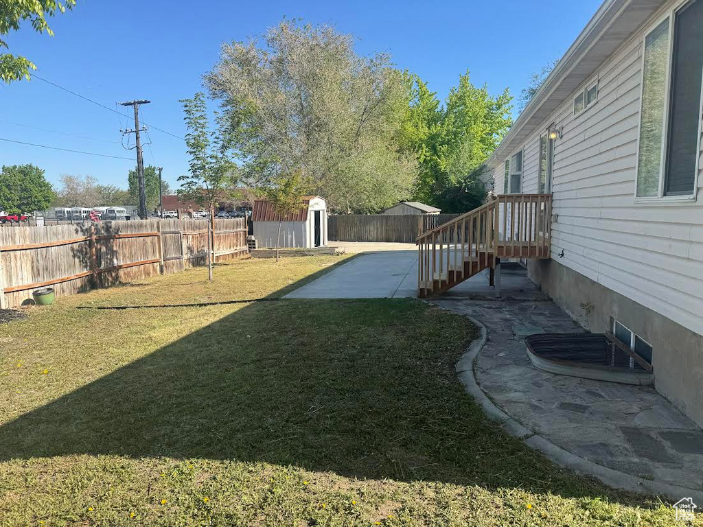 View of yard with a patio, a fenced backyard, an outbuilding, and a storage unit