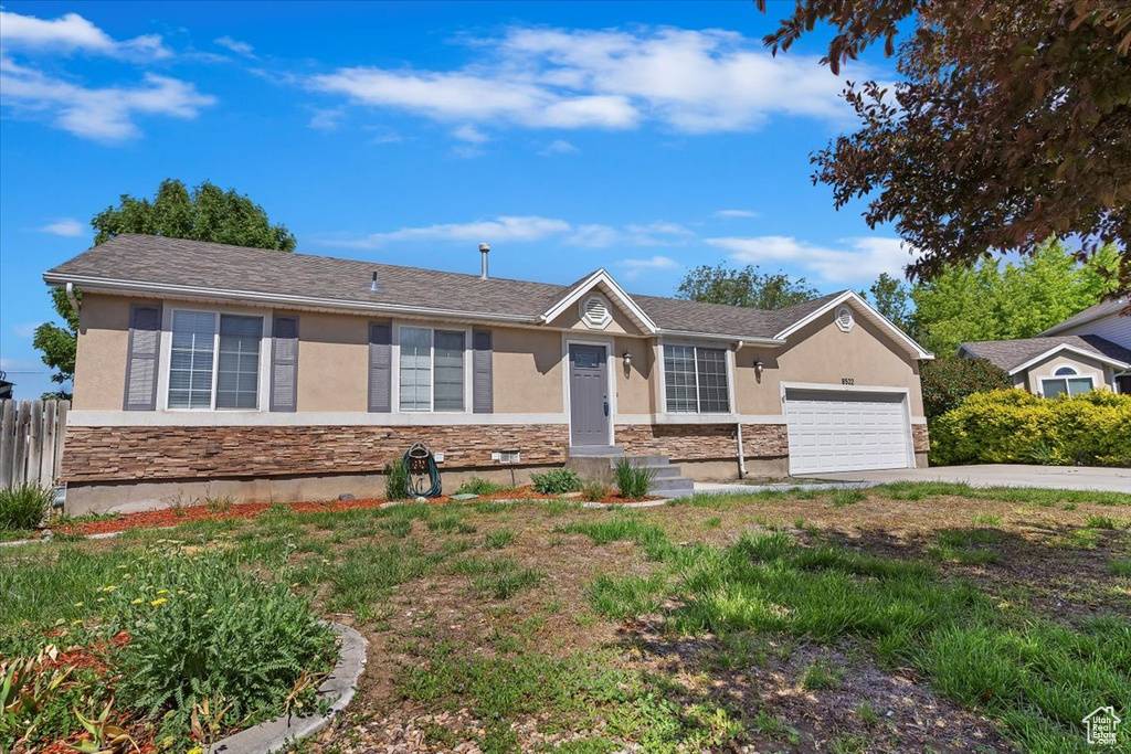 Ranch-style house featuring stone siding, stucco siding, a garage, and driveway