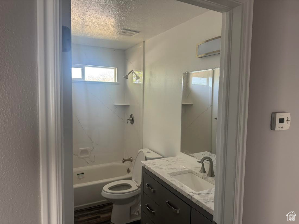 Bathroom featuring a textured ceiling, visible vents, vanity, toilet, and bathing tub / shower combination