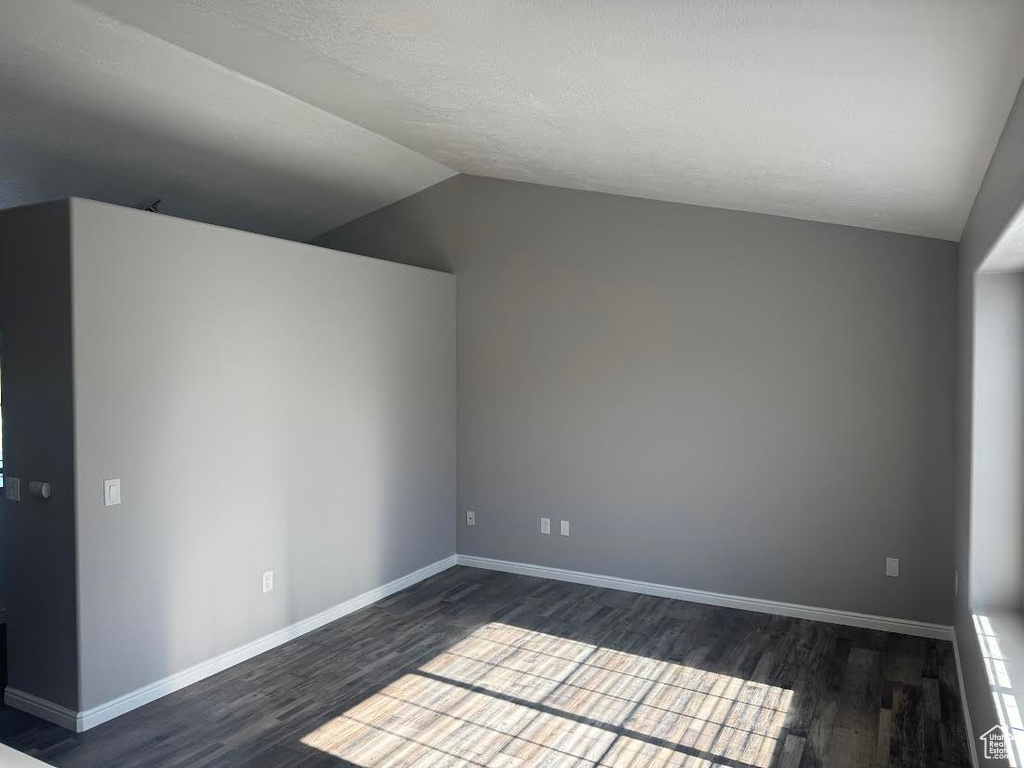 Additional living space with baseboards, dark wood-type flooring, a textured ceiling, and lofted ceiling