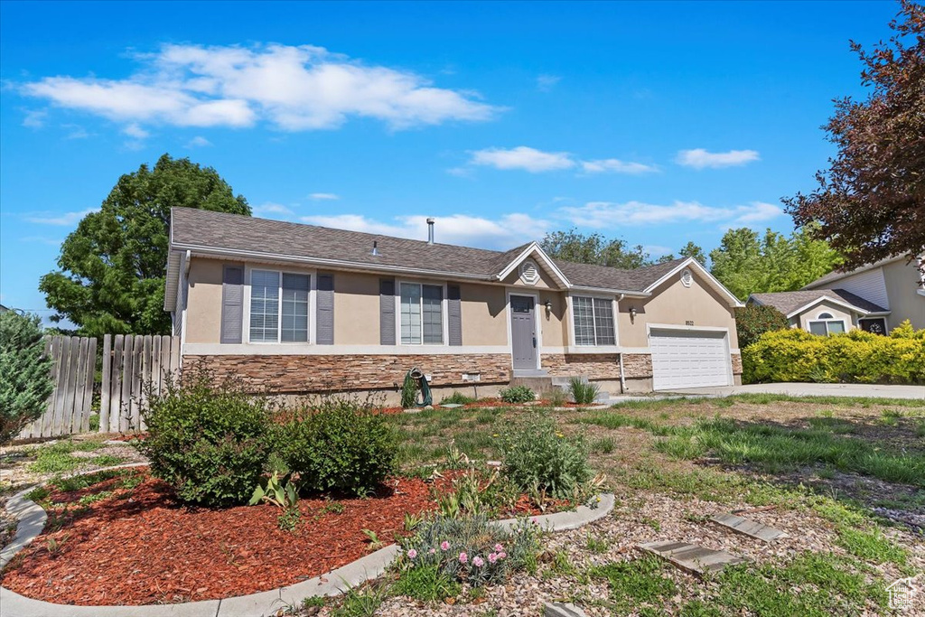 Single story home featuring stone siding, stucco siding, a garage, and driveway