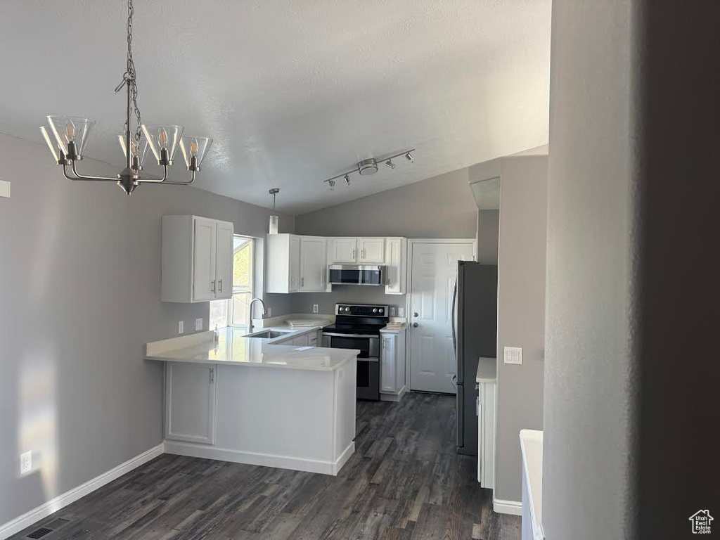 Kitchen featuring a peninsula, appliances with stainless steel finishes, a sink, and dark wood finished floors