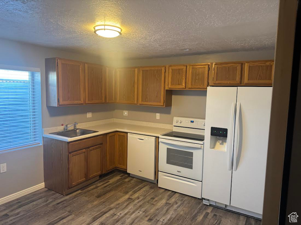 Kitchen featuring a sink, a textured ceiling, white appliances, and light countertops