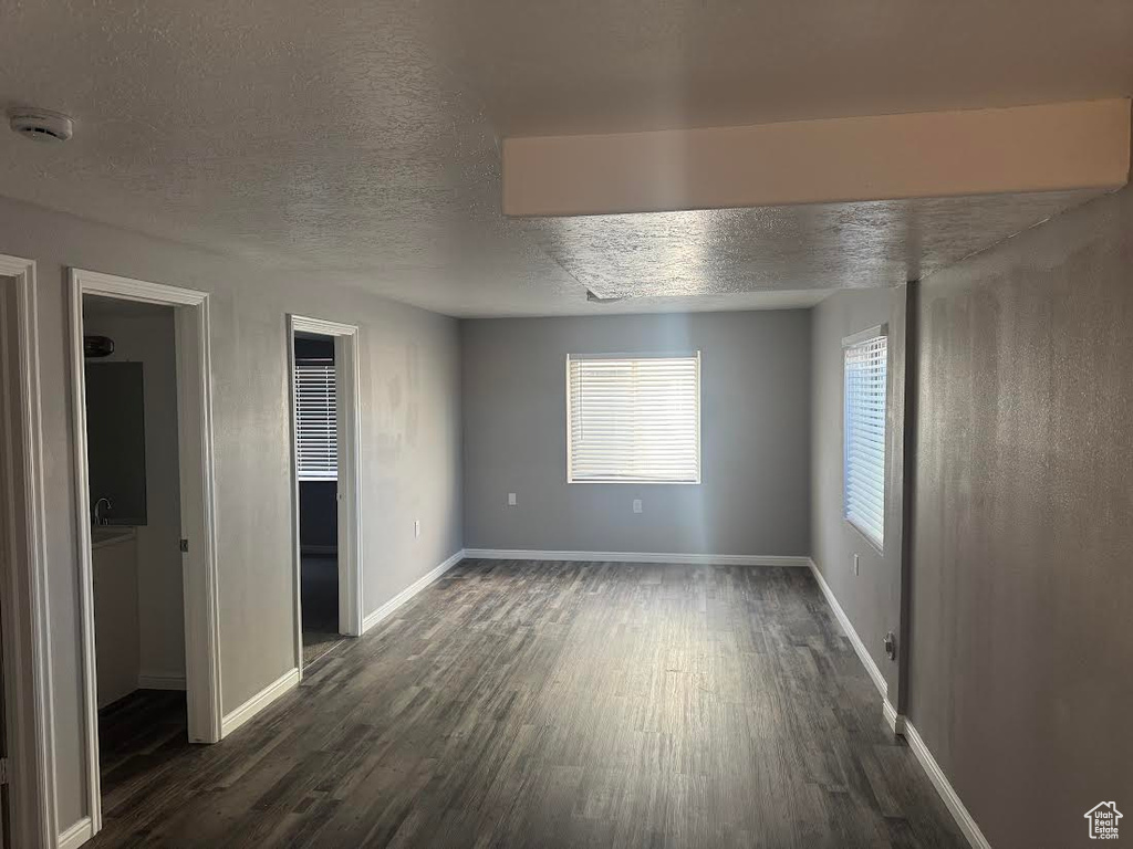 Unfurnished bedroom with a textured ceiling, baseboards, and dark wood-type flooring