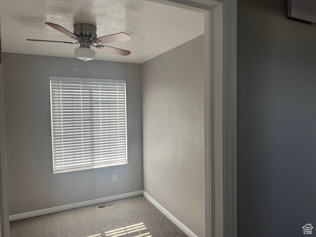Spare room featuring ceiling fan, a textured ceiling, visible vents, baseboards, and carpet floors