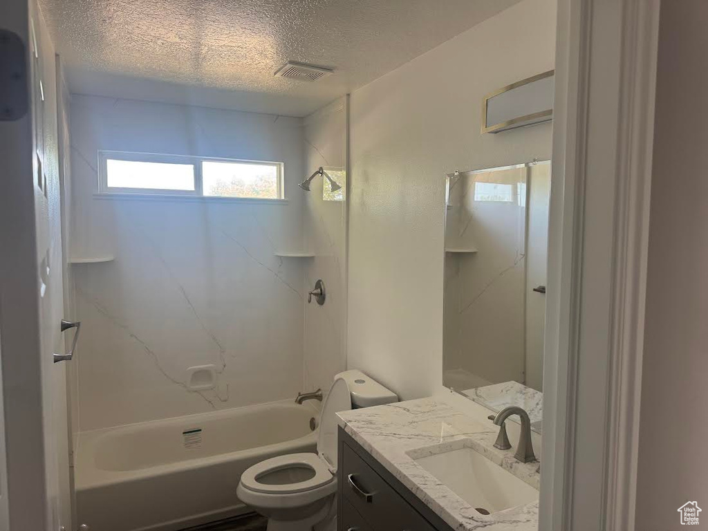 Full bathroom featuring visible vents, vanity, toilet, shower / tub combination, and a textured ceiling