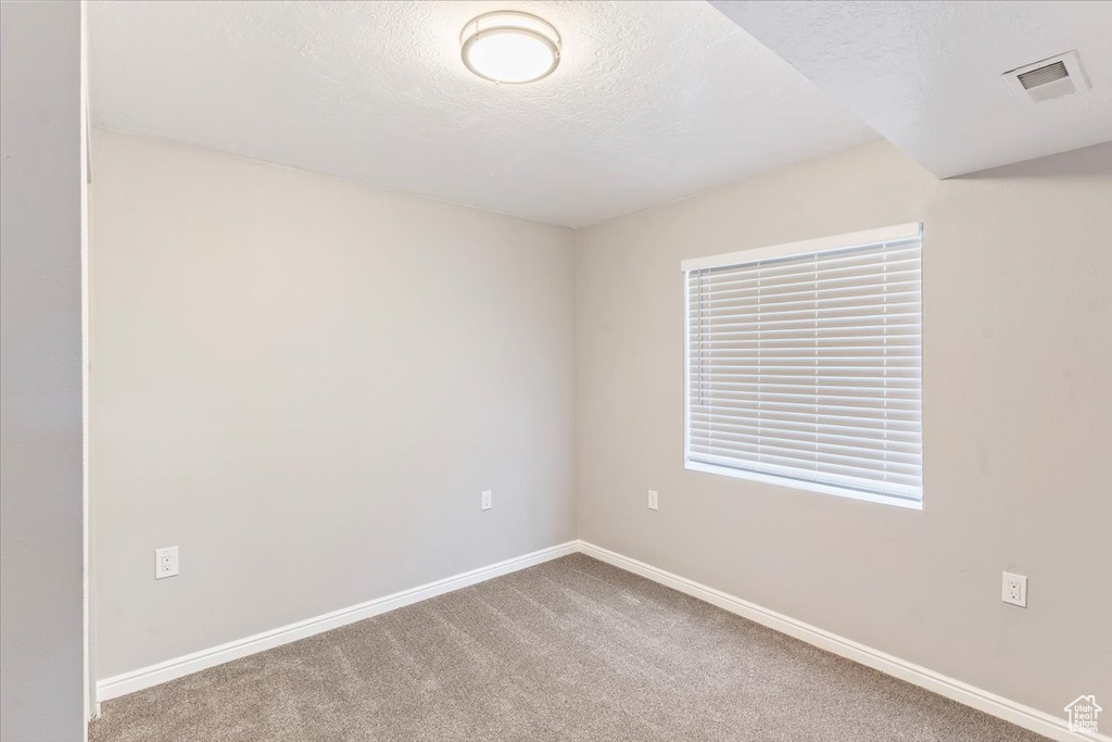 Unfurnished room featuring carpet flooring, baseboards, and a textured ceiling
