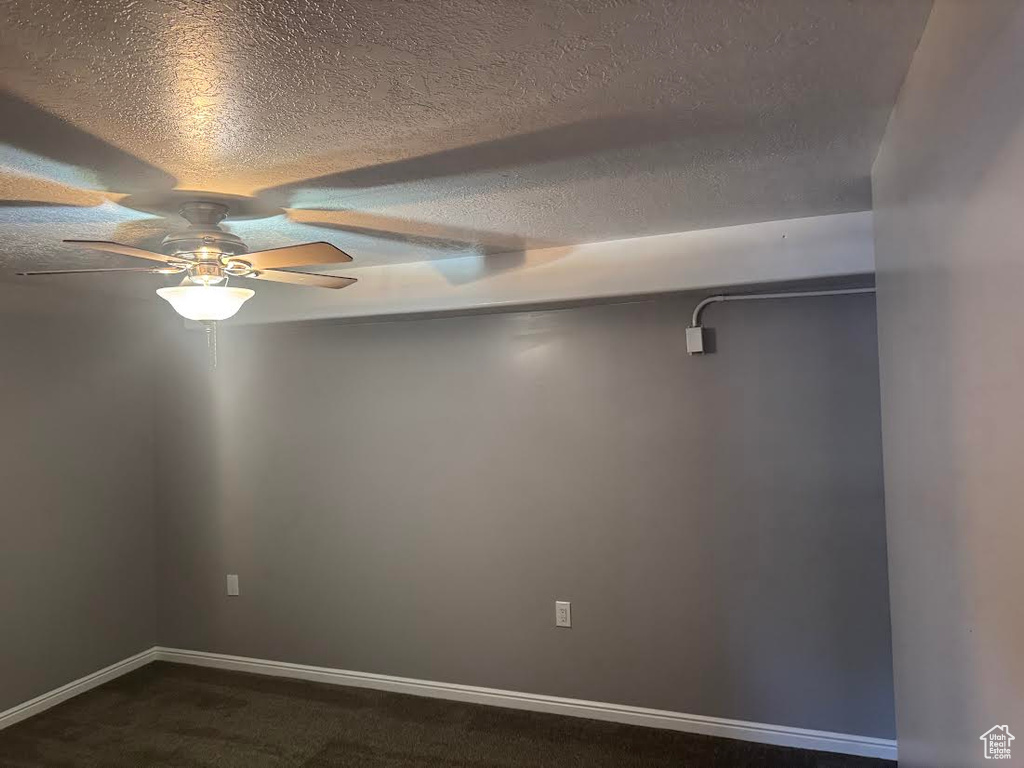 Spare room featuring a ceiling fan, a textured ceiling, baseboards, and dark colored carpet