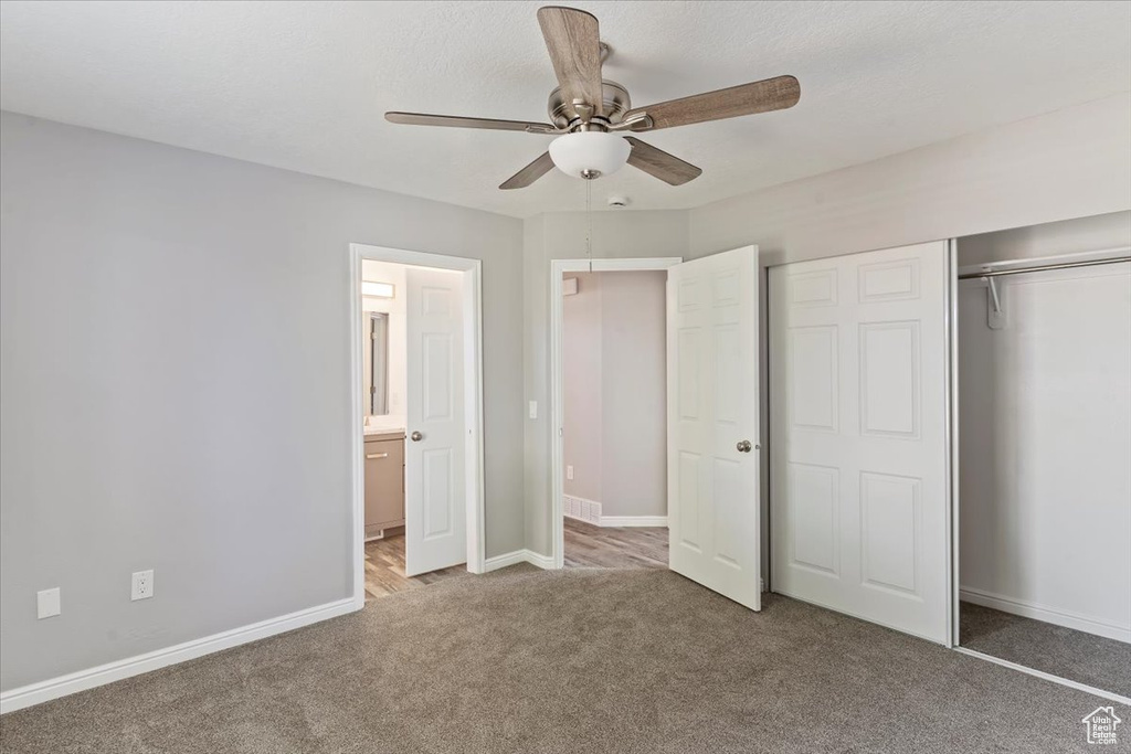 Unfurnished bedroom with carpet, a closet, baseboards, a ceiling fan, and ensuite bath