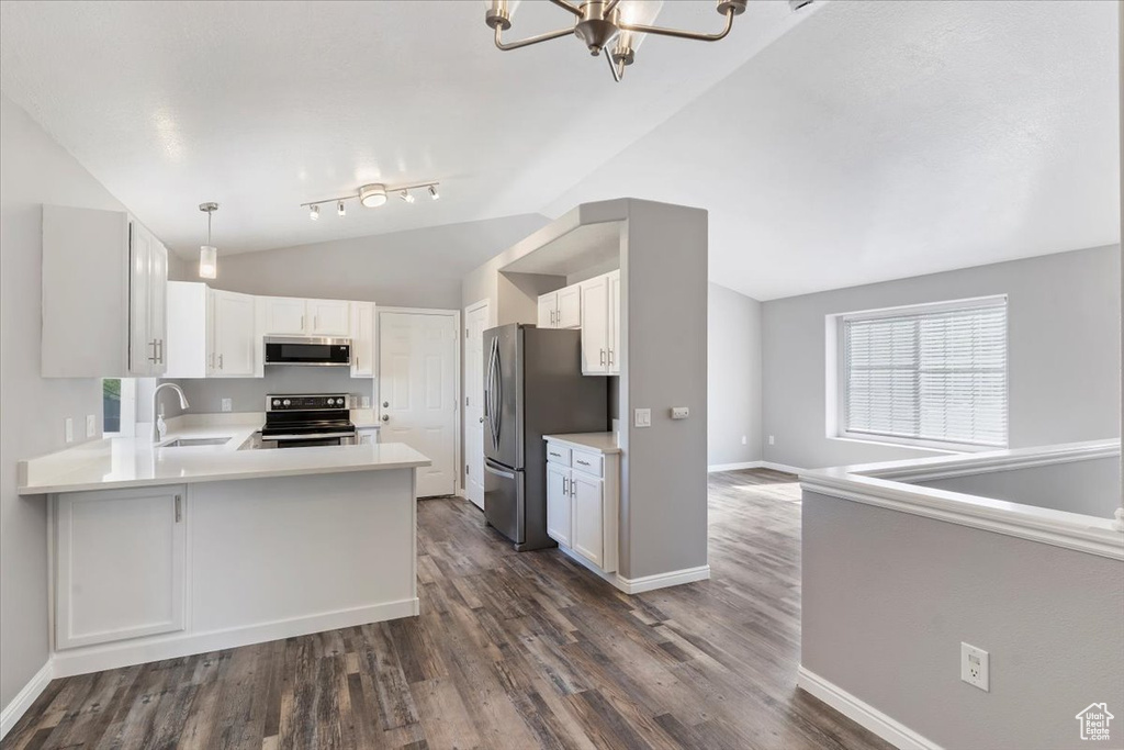 Kitchen featuring appliances with stainless steel finishes, lofted ceiling, a sink, a chandelier, and dark wood-style flooring