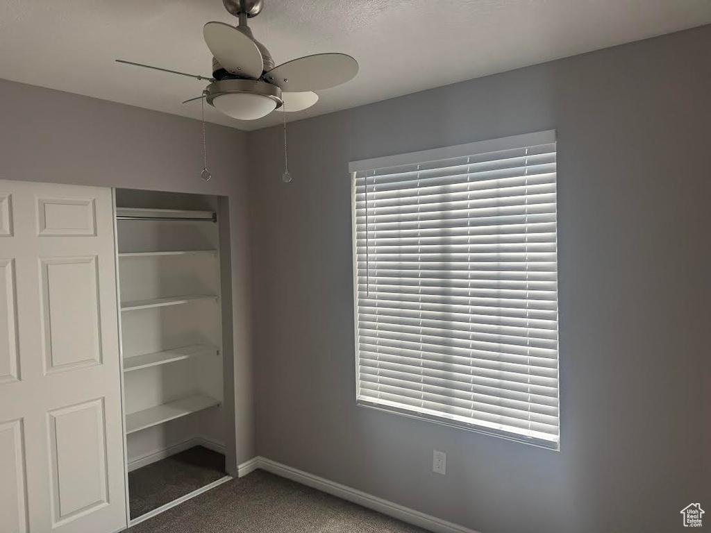 Unfurnished bedroom featuring baseboards, ceiling fan, carpet, and a closet