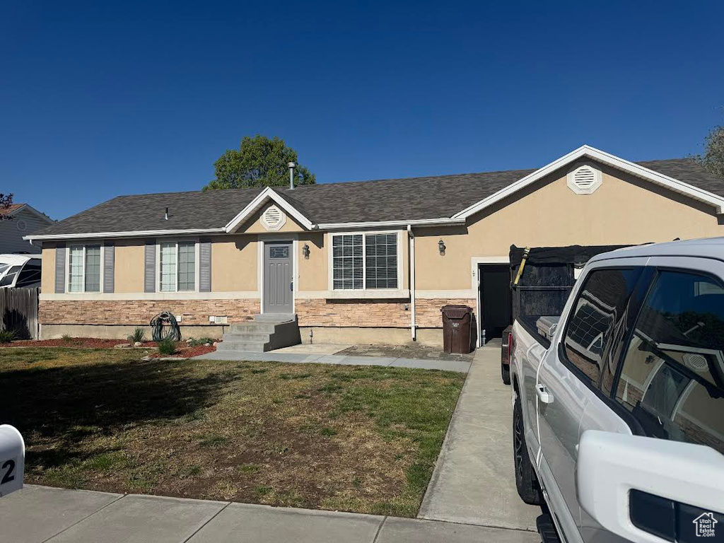 Ranch-style house with a garage, a front lawn, and stucco siding