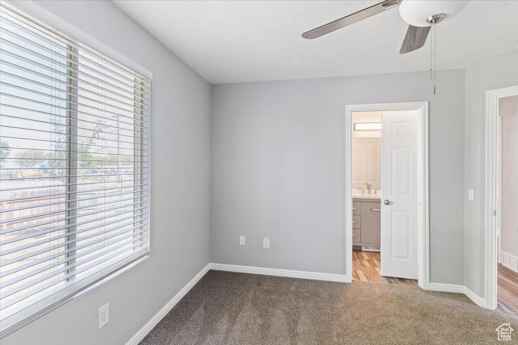 Unfurnished bedroom featuring carpet, multiple windows, baseboards, and ensuite bathroom