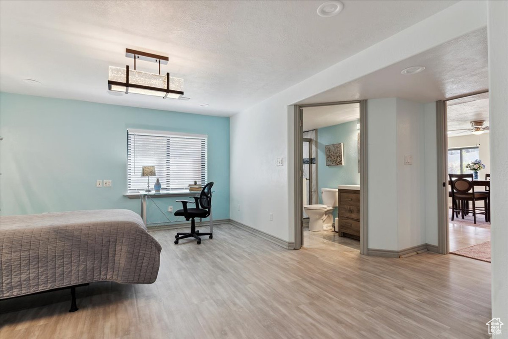 Bedroom with baseboards, ensuite bath, and wood finished floors