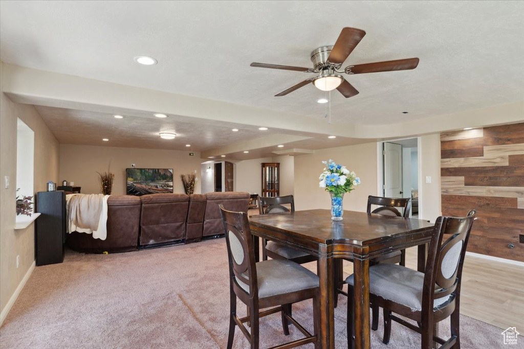 Dining room featuring ceiling fan, light colored carpet, wood walls, recessed lighting, and baseboards