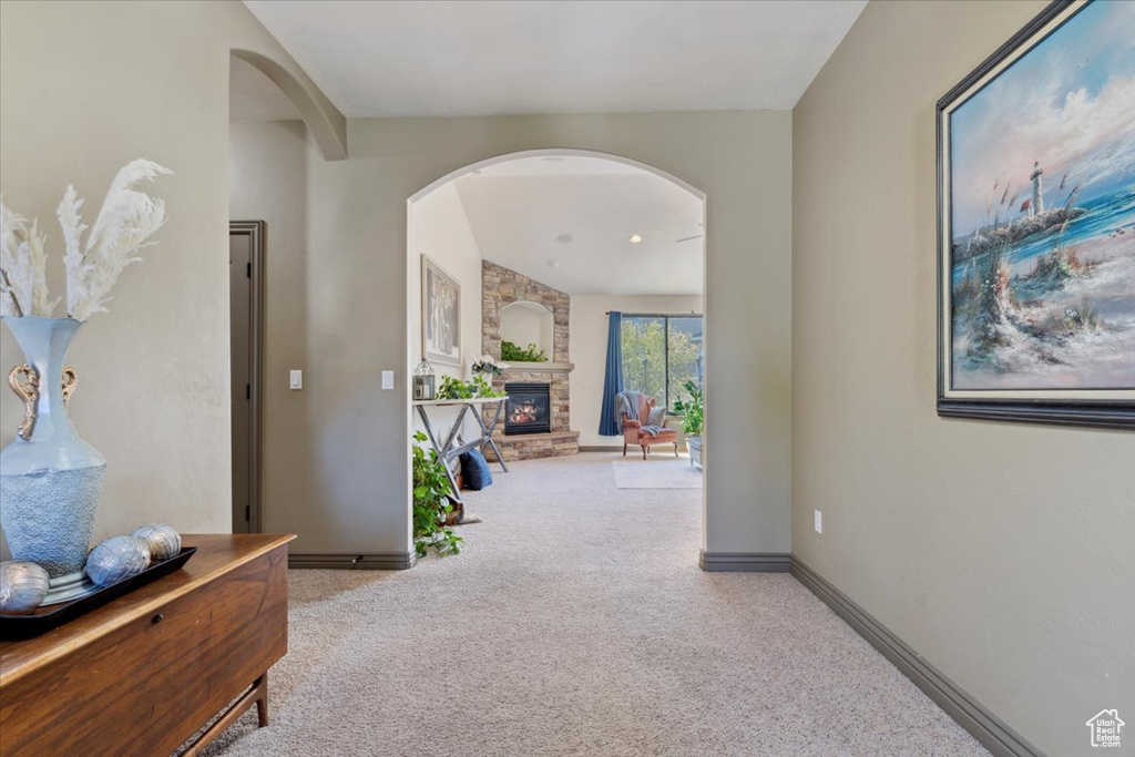 Hall with arched walkways, baseboards, and carpet flooring