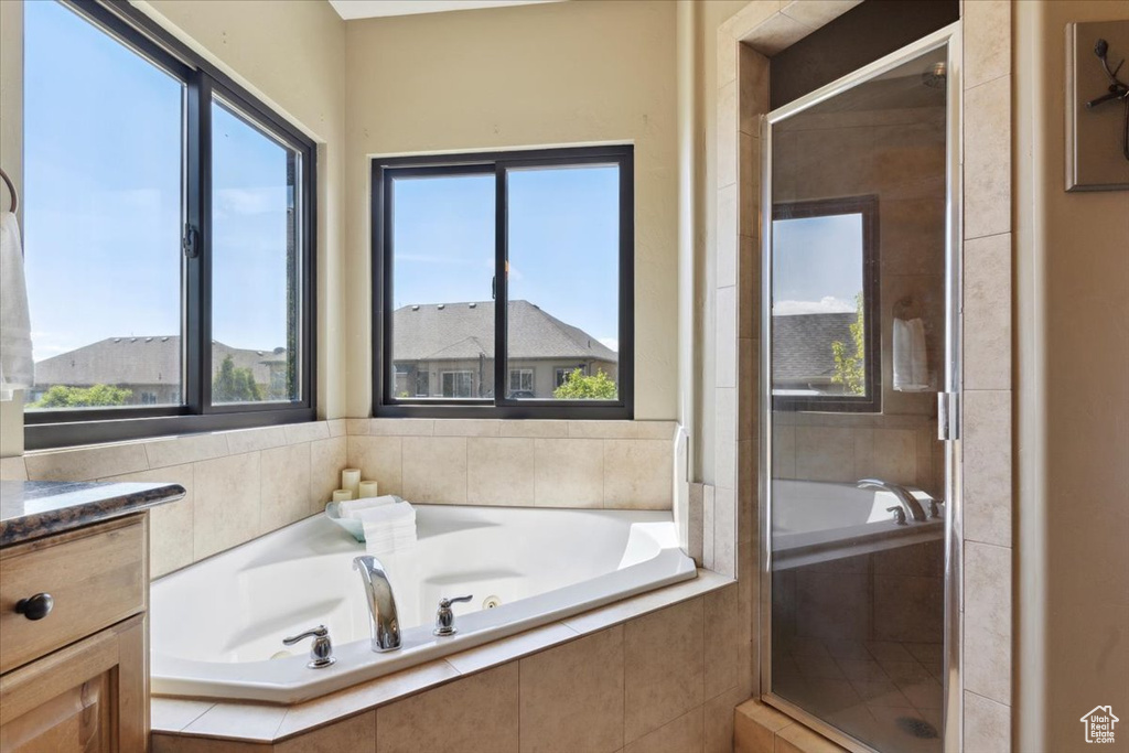 Bathroom with plenty of natural light, a shower stall, a bath, and vanity