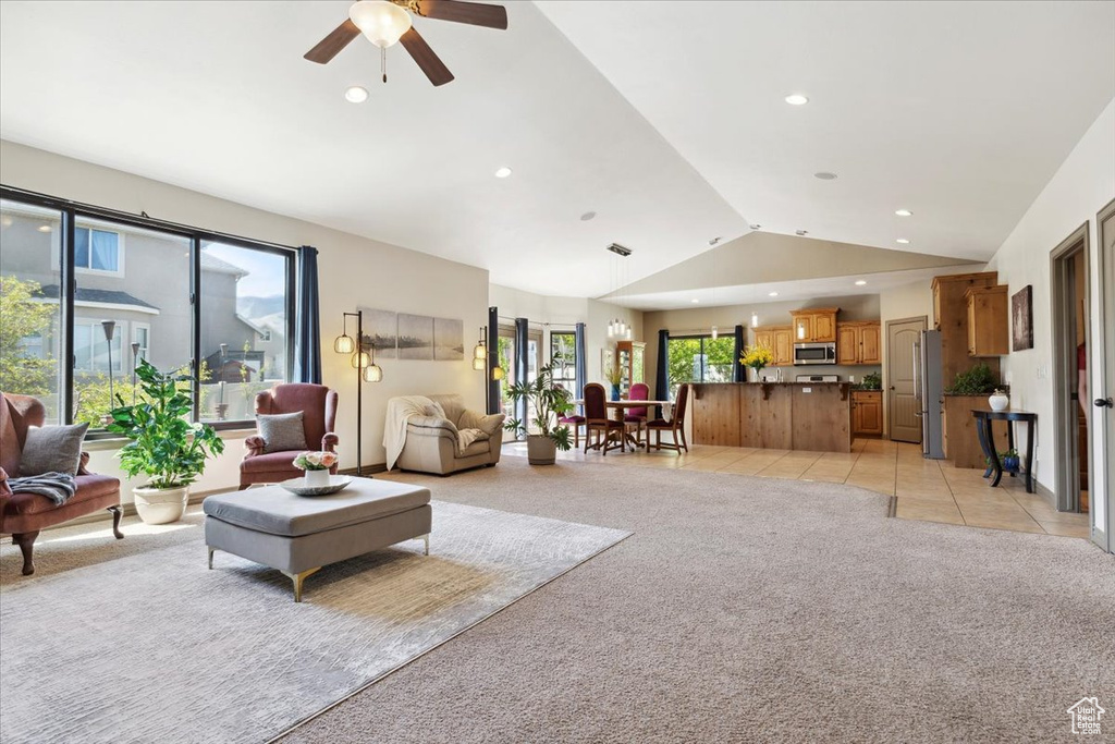 Living room with light carpet, a ceiling fan, vaulted ceiling, and a wealth of natural light
