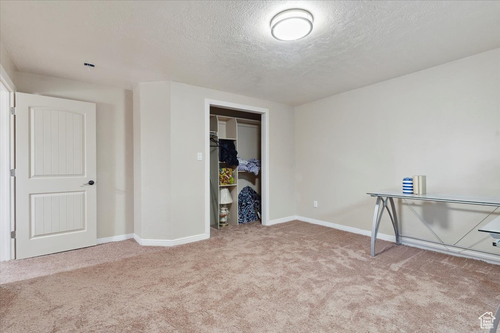 Interior space featuring baseboards, carpet flooring, and a textured ceiling