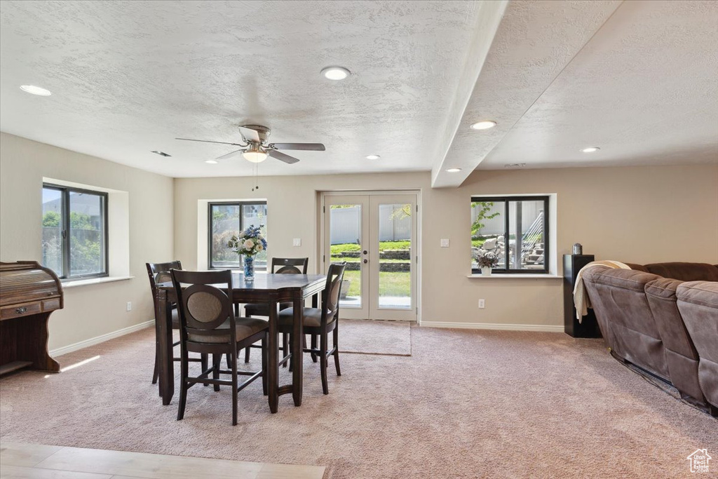 Dining space with a ceiling fan, french doors, a textured ceiling, baseboards, and light carpet