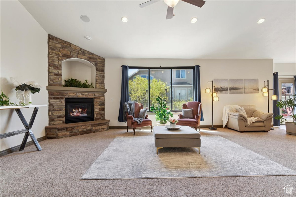 Carpeted living area featuring a stone fireplace, a ceiling fan, baseboards, recessed lighting, and vaulted ceiling