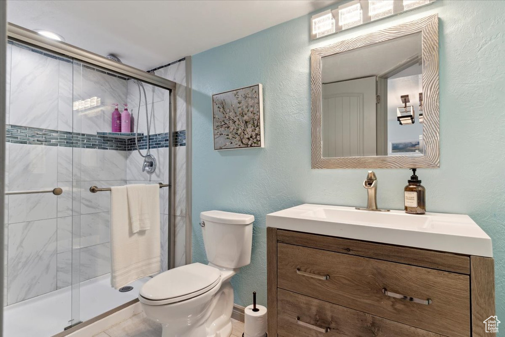 Full bathroom with a textured wall, a shower stall, and toilet