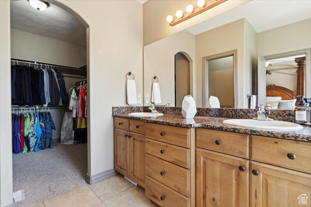 Bathroom featuring double vanity, a sink, a walk in closet, and tile patterned floors