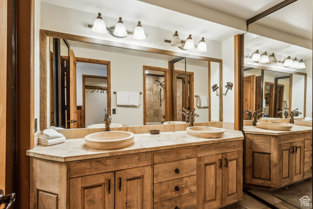 Full bathroom with double vanity, tiled shower, and a sink