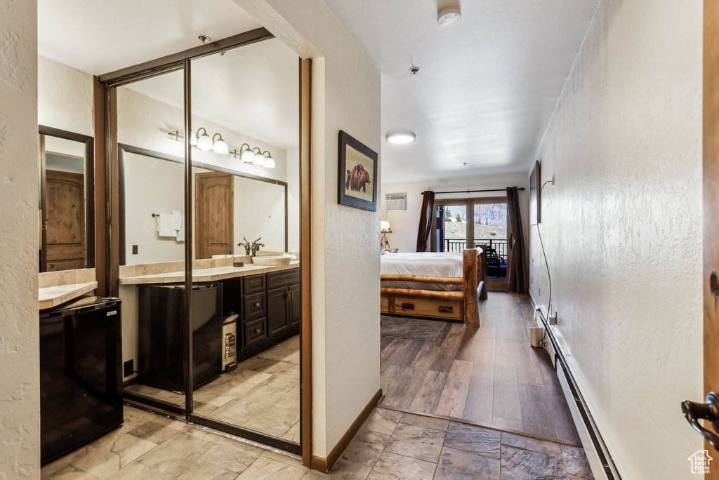Ensuite bathroom featuring baseboard heating, baseboards, connected bathroom, and vanity