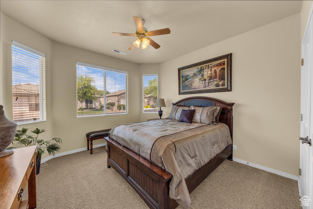 Bedroom featuring baseboards, a ceiling fan, light colored carpet, and visible vents