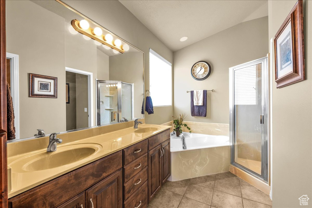 Full bath with a garden tub, double vanity, tile patterned flooring, a shower stall, and a sink