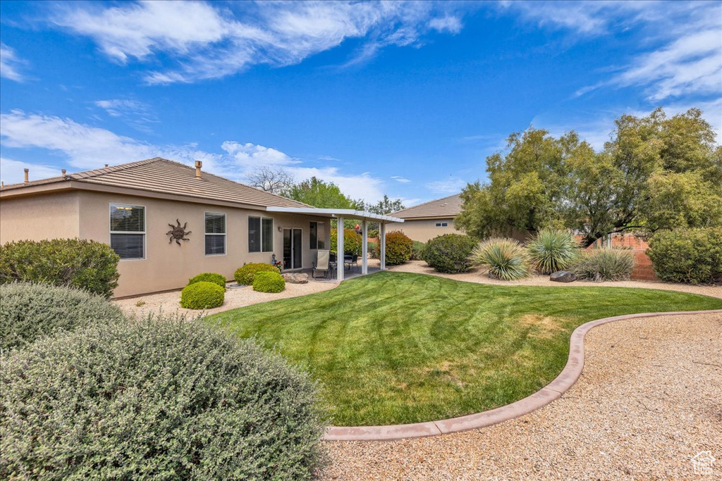 Back of house with a lawn, a patio, stucco siding, and a tile roof