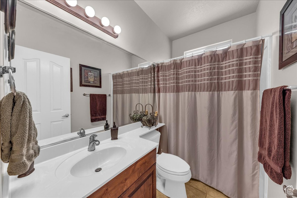Bathroom with toilet, tile patterned floors, a shower with shower curtain, and vanity